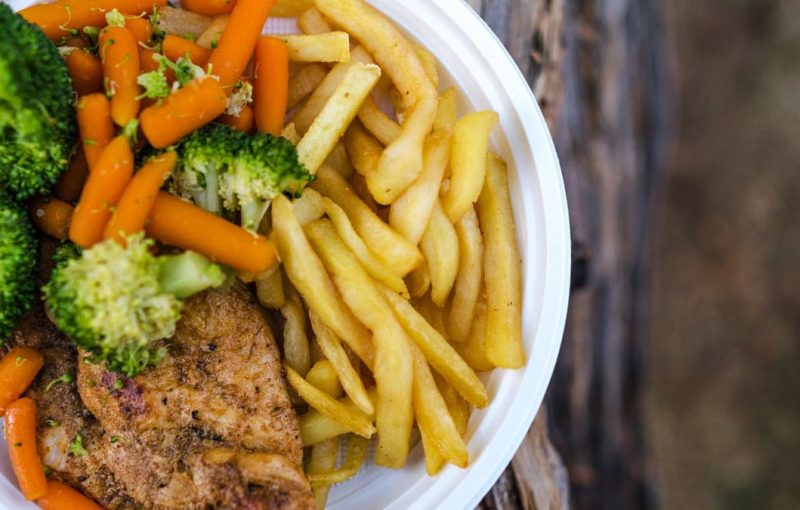 Delicious chicken dinner with broccoli, carrots, and fries on a plate.